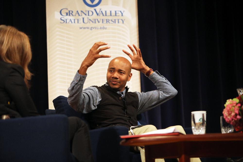 DJ Spooky aka Paul D. Miller with hands raised as if he were putting on a helmet